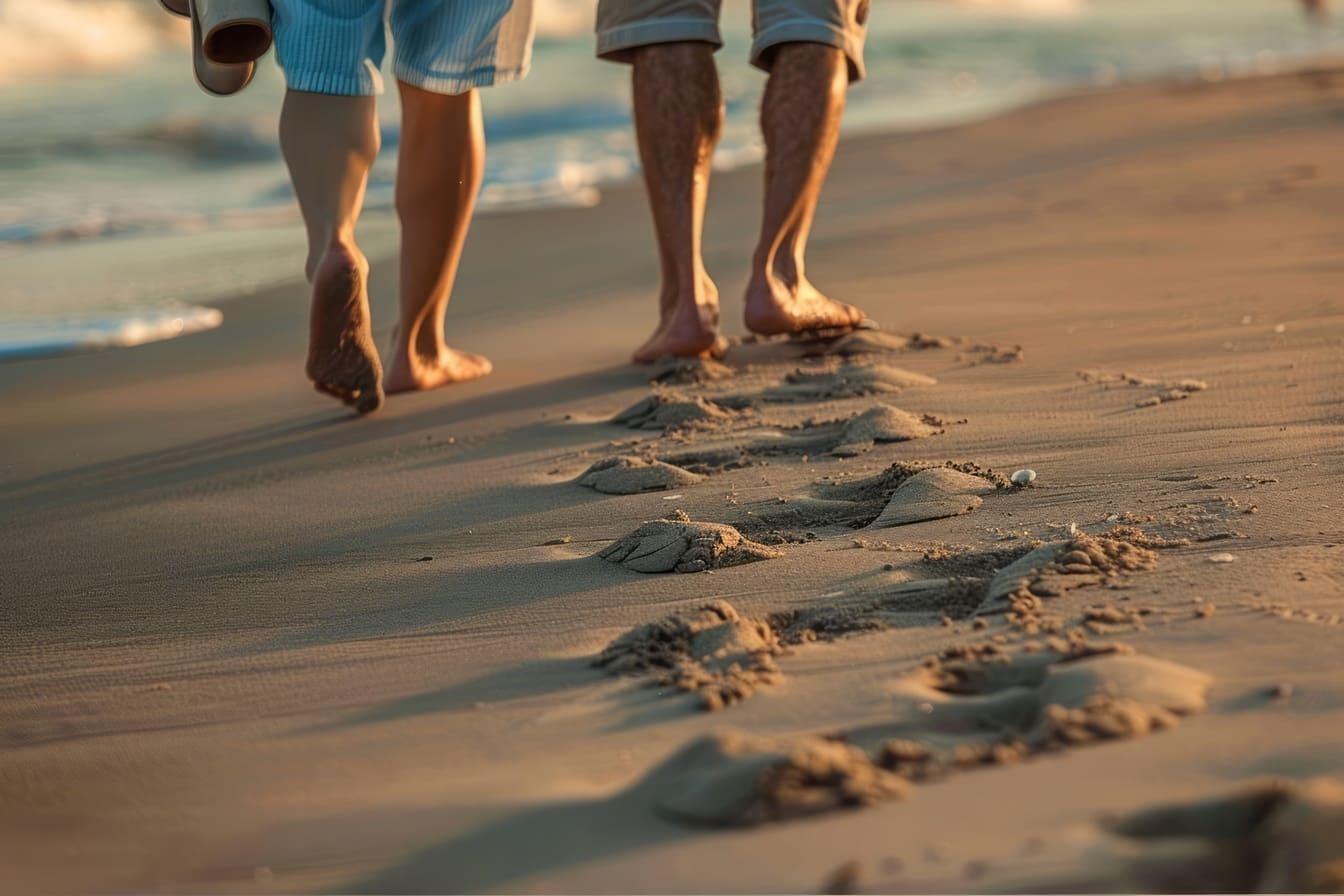 Personnes seniors pieds nus marchant sur une plage de sable